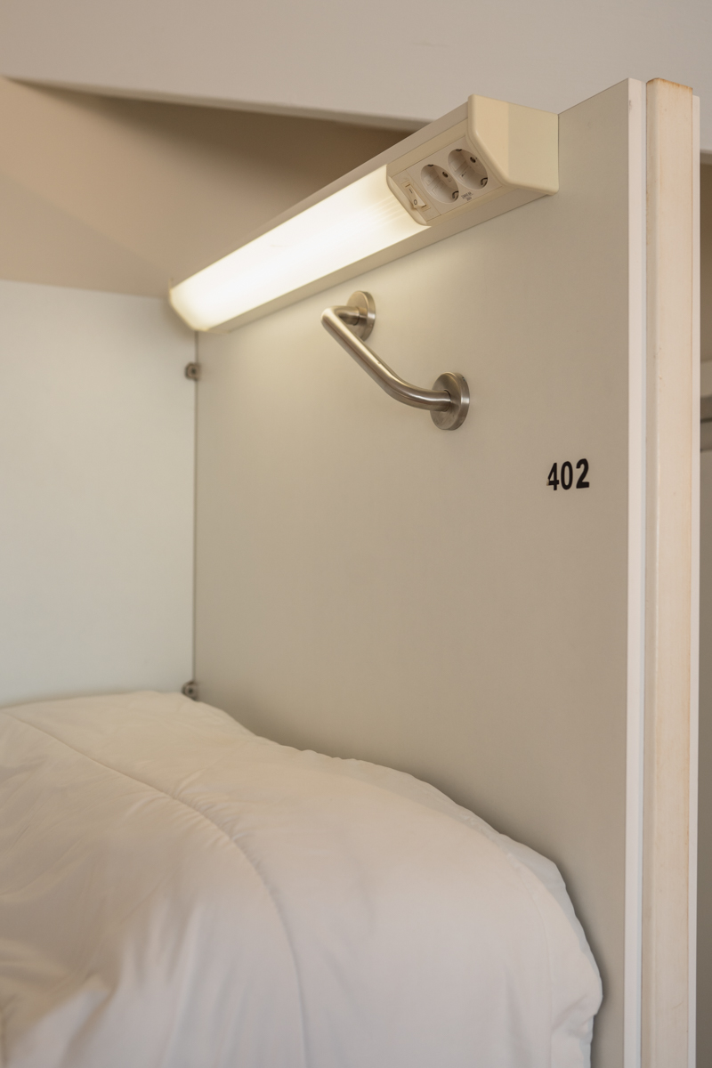 Fotografía detalle de la luz personalizada de una cama individual, con dos enchufes..